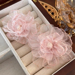 Detailed macro of light pink organza flower earrings with pearls in a wooden jewelry box