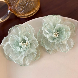 Detailed close-up of light green organza flower earrings with white beaded stamens