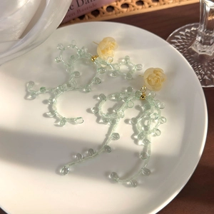 Détail de boucles d'oreilles fleurs vert menthe avec roses en perles et pampilles