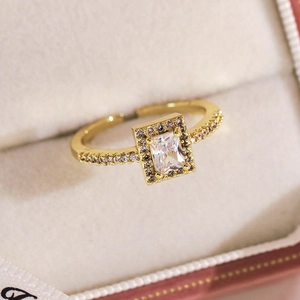 Gros plan d'une bague dorée avec zircon rectangulaire et accents de cristaux pavés