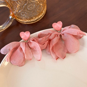 Detail of pink heart stud earrings with soft layered chiffon flower petals on a ceramic dish
