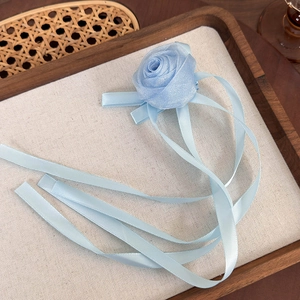 Détail d'une pince à cheveux rose en tulle bleu clair avec de longs rubans en satin