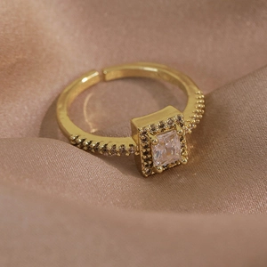 Détail d'une bague papillon dorée avec zircon carré et anneau ajustable sur de la soie