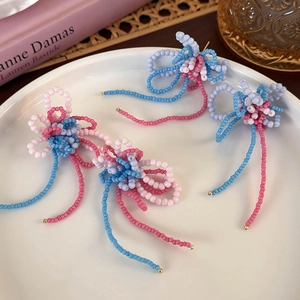 Macro shot of colorful beaded flower earrings with fringe on white ceramic plate