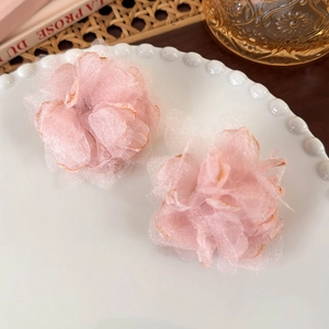 Close-up of pink layered mesh flower earrings on a vintage white ceramic tray