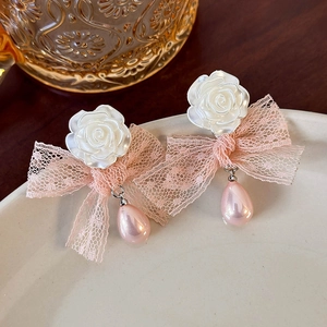 Close-up of mesh flower earrings with pink lace bows and teardrop pearl charms