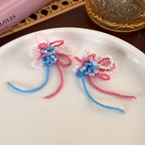 Detail shot of handmade colorful beaded flower earrings with fringe tassels in a ceramic tray