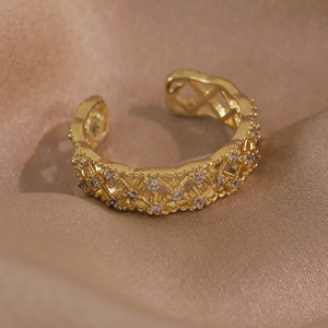 Détail d'une bague dorée ajourée avec zircons blancs sur un fond en tissu de soie