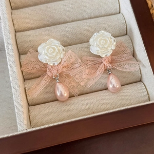 Detail of floral mesh earrings with pink lace bows and teardrop pearls in a jewelry tray