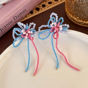 Detailed macro of handmade flower beaded earrings with long colorful fringe on white plate