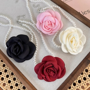 Close-up of elegant satin camellia flower pearl necklaces in various vintage colors