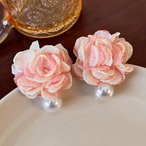 Close-up of pink gradient mesh flower earrings with pearls on white ceramic tray
