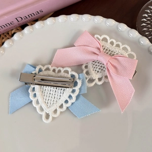 Detailed close-up of handmade lace heart and herringbone bow hair clips on a ceramic plate