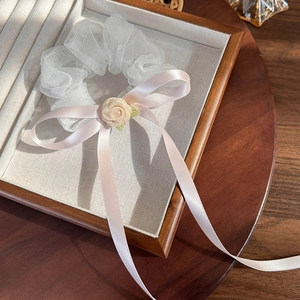 Détail d'un chouchou en organza blanc avec rose crème et longs rubans en soie rose
