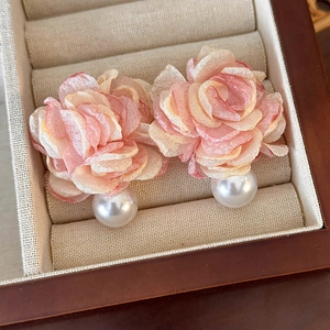 Detail of pink mesh flower earrings with a large white pearl drop in a jewelry box