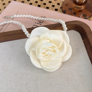 Detail of elegant satin camellia flower and lustrous pearls on a luxury necklace