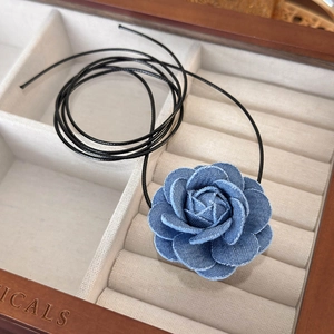Handmade denim flower choker necklace with black long cord in a wooden jewelry box