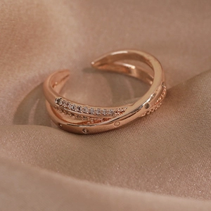 Détail macro de la bague croisée en or rose avec zircons pavés sur fond de soie élégant