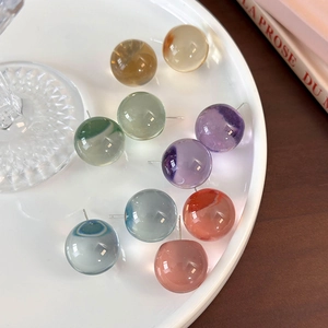 Flat lay of colorful translucent resin stud earrings on a white tray with props