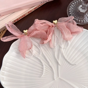 Detail of pink organza bow earrings with gold heart and white beaded tassels