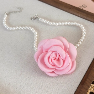 Close-up of pink satin camellia flower pendant and white pearls with adjustable clasp