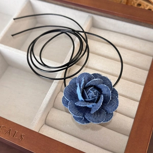 Detailed macro view of dark blue denim rose necklace with white stitched edges on lining