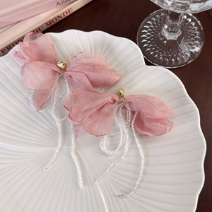 Detail of pink organza bow earrings with heart studs and long white beaded tassels