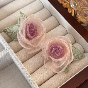 Detailed macro view of purple mesh flower earrings with green leaf embroidery