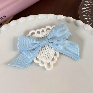 Detail of light blue bow hair clip with white crochet lace heart on a decorative tray