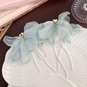 Detail of light green organza bow earrings with gold heart studs and long bead tassels