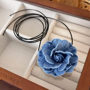 Detail of blue denim fabric rose choker necklace with frayed edges on black cord
