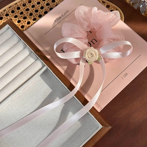Détail d'un chouchou en organza rose avec fleur de rose et nœud en ruban satiné