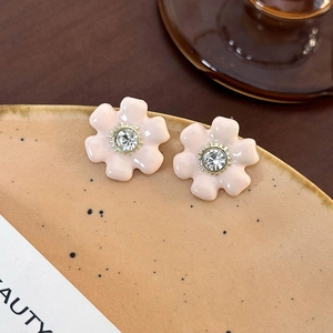 Gros plan de boucles d'oreilles fleurs roses avec cristal scintillant sur un plat en céramique