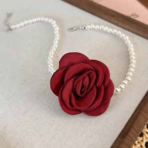 Close-up of deep red satin camellia and white pearls on a vintage French necklace