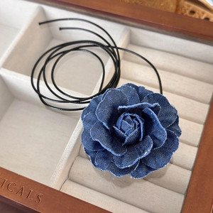 Macro detail of dark blue handmade denim flower choker with layered fabric texture