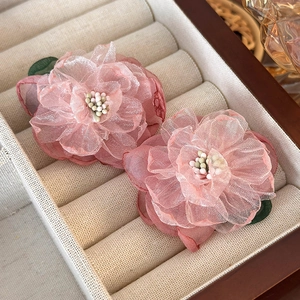 Detailed macro view of pink 3D fabric flower earrings with green leaf and bead accents