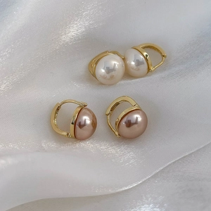 Dettaglio di orecchini con perle semitonde color champagne e bianche con clip a U dorate
