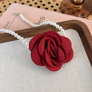 Detailed shot of a red satin rose pendant paired with white pearls for elegant vintage styling