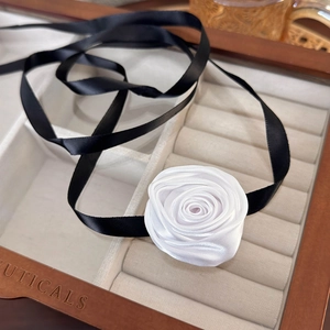 Macro shot of handmade white fabric rose choker with black ribbon in a wooden jewelry box