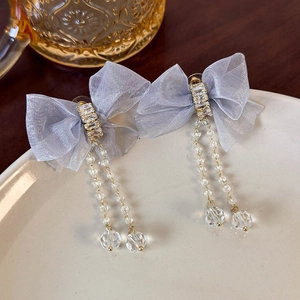 Close-up of blue mesh bow earrings with shimmering zircon center and long crystal tassels