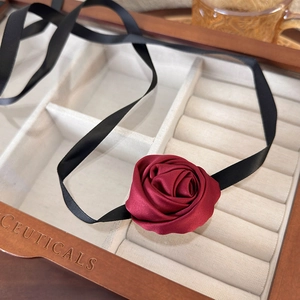 Detail of handmade deep red satin rose choker displayed in a luxury wooden jewelry box