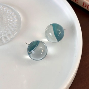Macro shot of transparent resin ball earrings with blue Morandi aesthetic inside