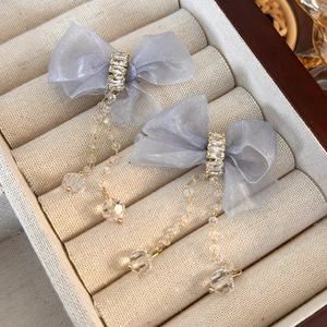 Detail of blue organza bow earrings with zircon center and gold chain fringe
