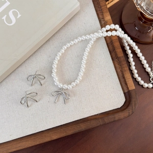 Elegant pearl necklace and bow pendant earrings set with high-gloss white pearls