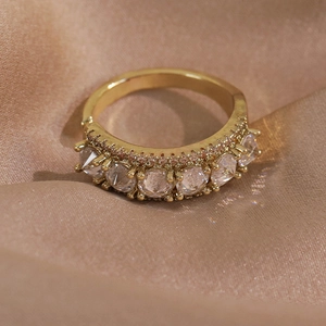 Gros plan d'une bague en cuivre doré sertie de zircons sur un tissu en soie beige