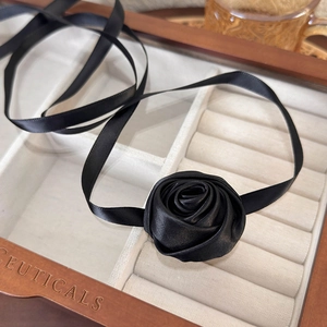 Close-up of handmade black satin rose choker necklace in a wooden jewelry display box