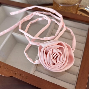 Detailed view of elegant pink satin rose choker necklace in a wooden jewelry box