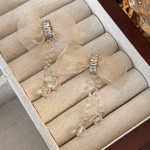 Detail of champagne mesh bow earrings with sparkling crystals and long gold tassels