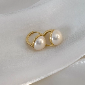 Dettaglio degli orecchini a cerchio con perla champagne su lussuoso tessuto di seta