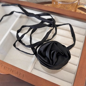 Detail view of a black satin handmade rose choker necklace with adjustable long silk ribbons